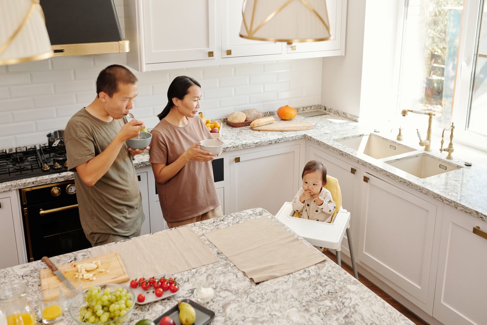 Parents and their toddler having breakfast together in a cozy family kitchen
